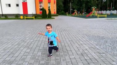 Asfaltlı meydanda koşan mutlu gülen çocuk. Evin yakınındaki beyaz erkek çocuk..