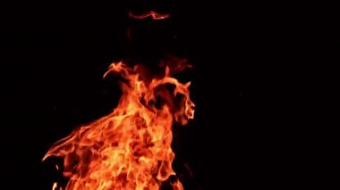 Sıcak kırmızı alev havada yatay ve dikey olarak yükseliyor. Karanlıkta dans eden güzel bir alev.
