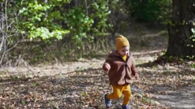 Sonbahar parkında koşan beyaz bir çocuk. Tatlı erkek bebek güneşli bir günde doğada iyi vakit geçiriyor..