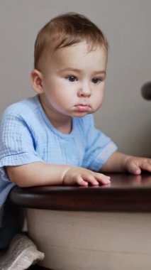 Düşünceli, şirin küçük bebek merdivenlerden eğilip onun önüne baktı. Sevimli çocuk ayağa kalkmayı öğreniyor. Dikey video