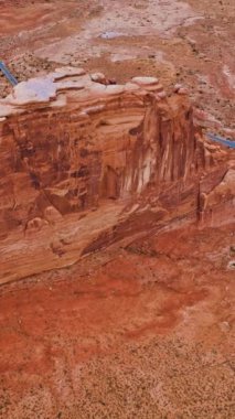 ABD 'nin Utah kentindeki Bryce Kanyonu' nun yüksek portakallı kayaları. Kayaların ve otobanın tepelerinden geçen arabalarla uçuyor. Hava görüntüsü. Dikey video