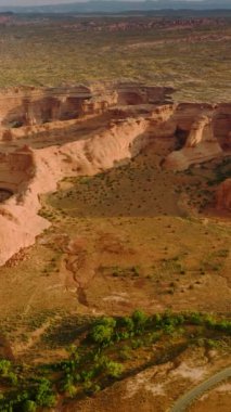 Utah, ABD 'nin harika kanyonlarının manzaralı resmi. Kayaların üzerinde İHA görüntüleri. Bölgeyi geçen yollar ve çölde nadiren yetişen yeşillikler. Dikey video