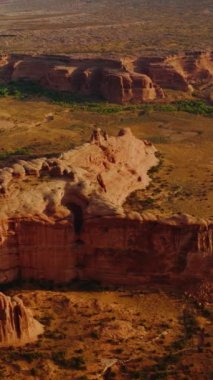 Utah, ABD 'de kemer kanyonları. Parlak güneş ışınlarındaki devasa kayaların muhteşem manzarası. Hava görüntüsü. Dikey video