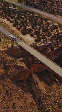 Köprüler çöl diyarındaki dev bir hendeğin kenarlarına birleşiyor. Küçük çalılarla kaplı arazinin üzerindeki drone görüntüleri. Dikey video