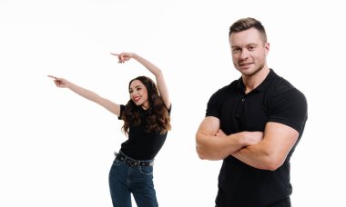 Beyaz Arkaplan 'ı işaret eden bir çift. Bir kadın ve siyah gömlekli bir adam, beyaz arka planda duruyorlar, ikisi de solu işaret ediyor..