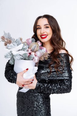 Noel Buketi Tutan Kadın. Siyah pullu elbiseli bir kadın elinde Noel çiçeğiyle dolu beyaz bir kutu tutarken gülümsüyor..