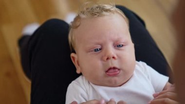 Güzel, beyaz, sarı saçlı, büyük mavi gözlü bir çocuk. Portreyi kapat. Bebek ana babaya dil gösteriyor.