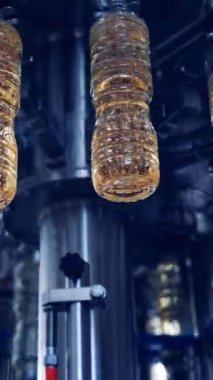 Petrol üretimi. Modern fabrikanın içinde zeytinyağı dolu plastik şişeler. Otomatik makine rafine yağla daireler çiziyor. Aşağıdan bak. Dikey video