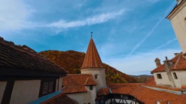 Romanya 'nın Transilvanya kentindeki Bran kalesinin çatıları. Renkli sonbahar doğası ve mavi gökyüzü arka planda.