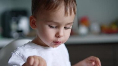 Üzerinde biraz yiyecek olan şirin bir bebek mamasının yüzü. Beyaz çocuk çorbasını kendisi içiyor. Kapatın. Bulanık arkaplan.