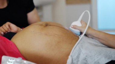 Doktorun eli, tanınmayan bir kadının karnında ultrason çevirici taşıyor. Bebek doğmadan önceki son evredeki hamileliği kontrol ediyorum..