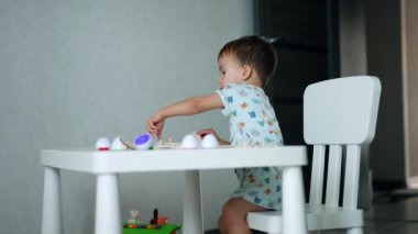 Odasında masasında oturan küçük beyaz bir çocuk. Tatlı çocuk bulmacalarla oynuyor..