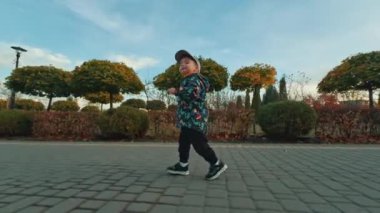 Parkta koşan tatlı küçük çocuk. Sonbaharda açık havada enerjik bir erkek bebek. Düşük açı görünümü.