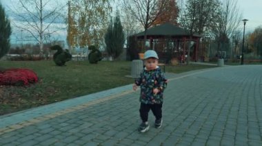 Parktaki sokakta koşan sevimli çocuk. Sonbahar doğasında koşarken etrafa bakan meraklı çocuk..