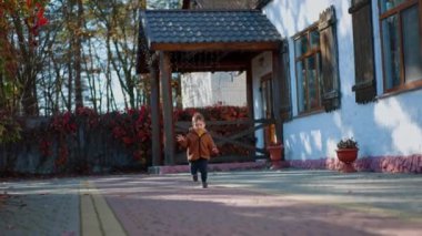 Sevimli gülümseyen çocuk kameraya doğru koşuyor. Mutlu erkek bebek sonbaharda açık havada vakit geçiriyor..