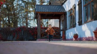 Sonbaharda avluda koşan neşeli beyaz çocuk. Güneşli bir günde enerjik ve aktif bir yürüyüş..