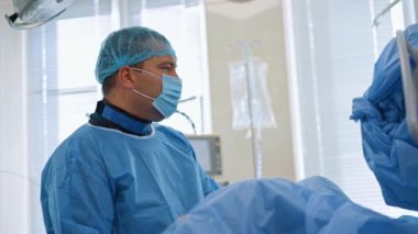 Endoskopi yapan odaklanmış bir doktor. Hastayı ameliyat eden bir cerrahın yan görünüm portresi.