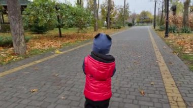 Kırmızı ceket giyen sevimli bir çocuğu takip etmek. Çocuk oyuncağını yere koyar ve kameraya döner..