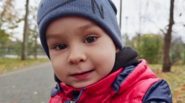 Mavi şapkalı beyaz bir erkek bebeğin güzel yüzü. Kapatın. Sonbaharda açık havada mutlu bir çocuğun portresi..