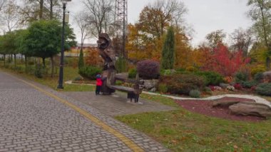 Dışarıdaki ahşap heykelin yanında duran sevimli küçük bebek. Arka planda güzel bir sonbahar parkı.