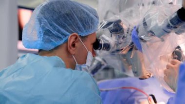 İşbirliği yapan iki beyin cerrahı mikroskop dürbünlerine dikkatlice bakar. Modern kliniklerde sinir cerrahisi.