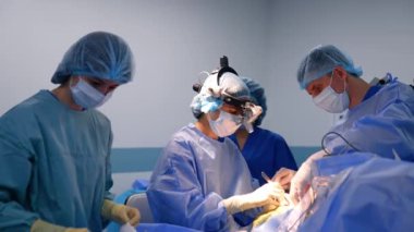 Cihaz gözlüğü takan kadın beyin cerrahı ameliyat hastası. Doktora ameliyatta yardım eden tıbbi ekip..
