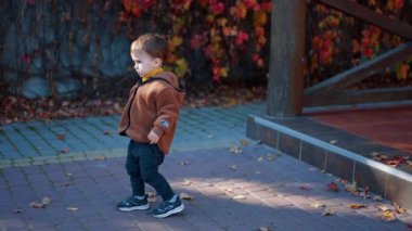 Aktif enerjik Kafkasyalı çocuk sonbaharda yürüyüşe çıkıyor. Mutlu çocuk neşeyle verandada zıplıyor..