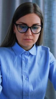 Sayfaları çevirmek için gerekli belgeleri arayan sarışın bir kadın. Ofiste çalışan meşgul bir iş kadını. Dikey video