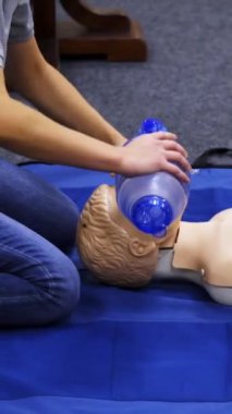 Hayat kurtarmak için eğitim seansı. Eğitmen bir manken üzerinde kalp egzersizi gösteriyor. Solunum cihazlı bir kuklanın suni teneffüs uygulaması. Dikey video