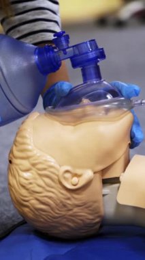 Manikin üzerine eğitim kursu. Uygulayanlar canlandırmada bir kuklayla nefes egzersizi yapıyor. Bir mankene yapılan kalp krizi sırasında baskı. Dikey video
