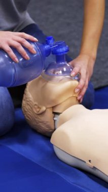 Kardiyopulmoner resüsitasyon. Eğitmen bir kuklanın üzerinde ilk yardım canlandırması gösteriyor. Tıp çalışanı bir manken üzerinde kalp egzersizi gösteriyor. Dikey video