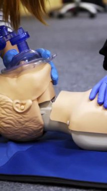 Bir mankene eğitim kompresyonu. Tıp merkezindeki bir mankene suni teneffüs uygulaması. Kalp krizi sırasında öğretme becerileri. Dikey video