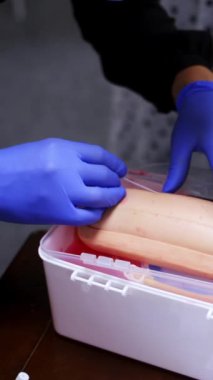 Enjeksiyonla pratik dersi. Pratisyen bir kuklanın damarına iğne yapıyor. Manikin koluna iğne batırma işlemi. Yakın plan. Dikey video