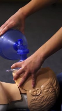 Bir mankene eğitim prosedürü. Eğitim merkezindeki bir manken üzerinde tıbbi canlandırma gösterisi. Eğitmen tıbbi aletlerle nefes alma egzersizi gösteriyor. Dikey video