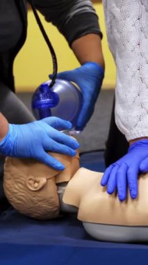 İlk yardım canlandırması. Güvenlik eldivenli kadınlar manken üzerinde canlandırma tekniği deniyor. Manken üzerinde kardiyopulmoner eğitim. Sağlık ve tıbbi konsept. Dikey video