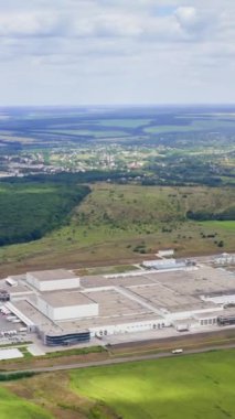 Doğadaki bir fabrikanın panoramik görüntüsü. Yeşil alanlarda büyük sanayi bölgesi. Kırsal kesimde imalat. Hava görüntüsü. Dikey video