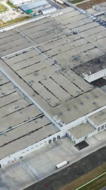 Sanayi kompleksi. Endüstriyel binaların çatıları ve sahada araba parkı. Yukarıdan büyük bir fabrika. Üst Manzara. Dikey video