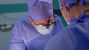 Cihaz gözlüklü doktor hastanın üzerine eğildi. Ameliyathanede odaklanmış beyin cerrahı..