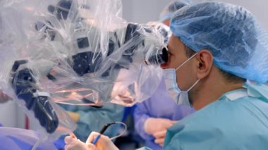 Dikkatli bir beyin cerrahı mikroskoba bakarak mikro cerrahi yapar. Nöroşirürji yapan bir doktorun yan görüntüsü.