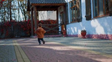 Dışarıda koşan küçük bir çocuğun arka görüntüsü. Mutlu enerjik bebek sonbaharda aktif zaman geçiriyor..