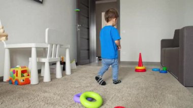 Odasında oynayan sevimli, beyaz bir çocuk var. Tatlı erkek bebek oyuncak piramidiyle oynuyor.