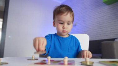 Ciddi çocuk masadaki oyununa odaklanmış durumda. Yapboz oynayan tatlı bir çocuk. Düşük açı görünümü.