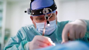 Erkek Kafkasyalı cerrah otolargolojik prosedür uyguluyor. Bir doktorun elindeki metal aletler. Kapatın. Bulanık arkaplan.