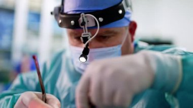 Ameliyatta meşgul olan bir erkek cerrahın konsantre yüzü. Burun ameliyatı yapan bir doktorun yakın portresi..