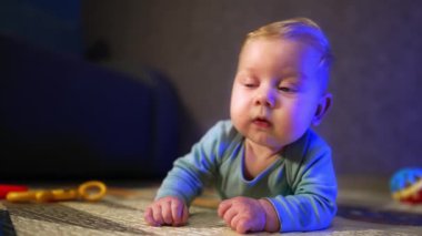 Şirin mavi gözlü, beyaz bir bebek göbeğinde yatıyor. Meraklı çocuk etrafına bakıyor. Bulanık arkaplan.