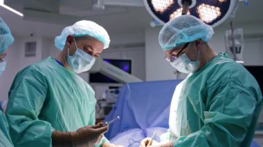 Travmayı operasyonel yöntemlerle tedavi eden cerrahlar. İki doktor iş yerinde metal tıbbi aletler kullanıyor. Bayan hemşire asistanı..