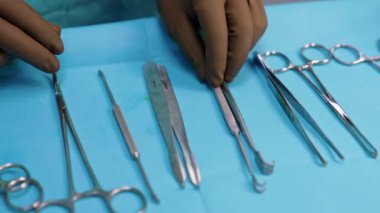 Kahverengi lateks eldivenli eller metal enstrümanlara dokunur. Ameliyat masasındaki aletler ortopedik ameliyat için hazır. Kapat..