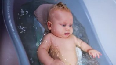 Sarışın bebek banyoda hareket ediyor. Bebek için banyo zamanı geldi. Kapat..