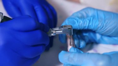 Matkap ve kemik tutan lateks eldivenli iki çift el. Matkap delik açmak için kullanılır ve kırmızı sıvı görünür. Kapat..