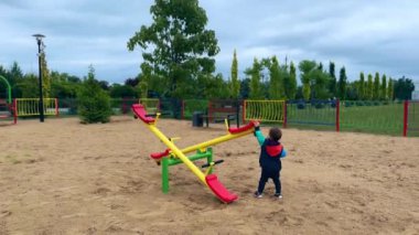 Bebek çocuk parkta tahterevalliyle oynuyor. Güzel beyaz çocuk, dışarıda..